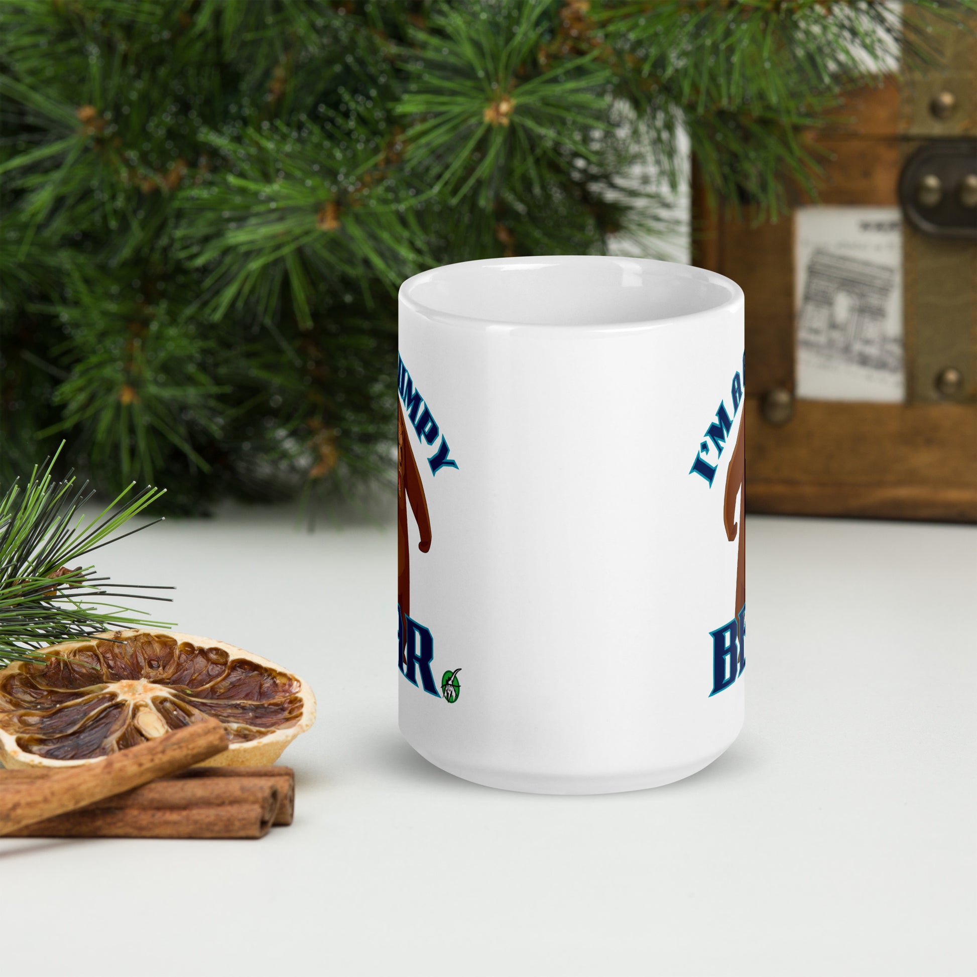 Wizard Prints white mug with grumpy bear graphic and 'I'm a grumpy bear' text on a surface with decorative nature elements.