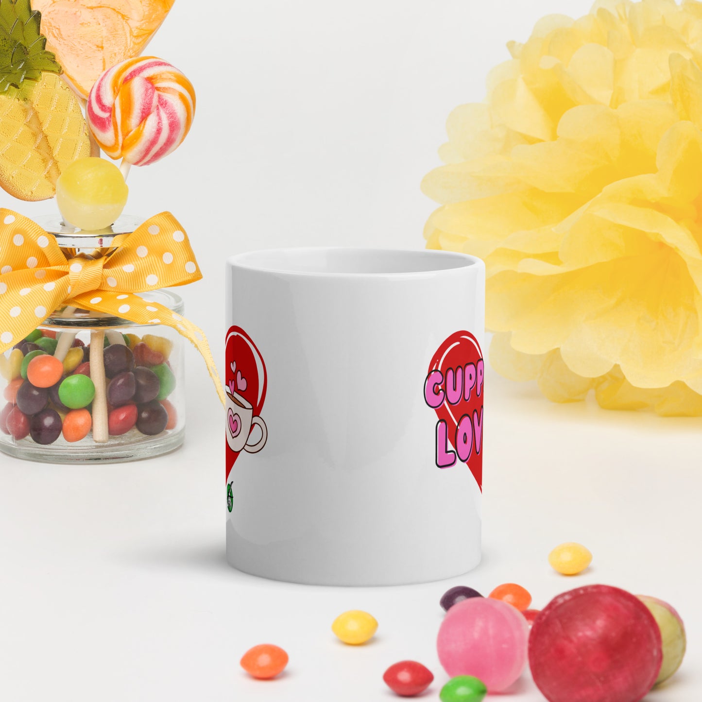 White Wizard Prints mug with a love heart design and 'Cuppa Love' text surrounded by colourful candies and flowers on a white background.
