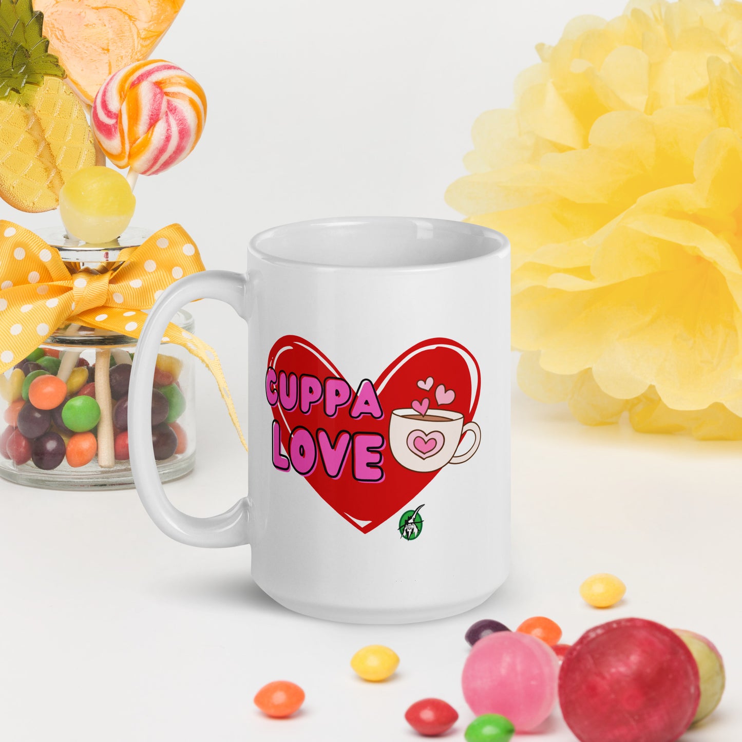 White Wizard Prints mug with a love heart design and 'Cuppa Love' text surrounded by colourful candies and flowers on a white background.