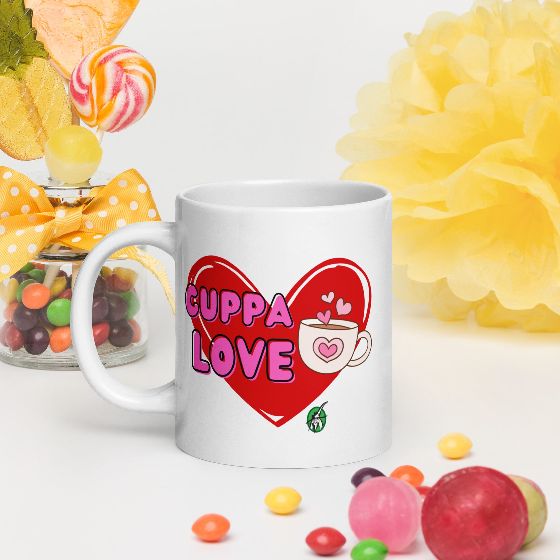 White Wizard Prints mug with a love heart design and 'Cuppa Love' text surrounded by colourful candies and flowers on a white background.