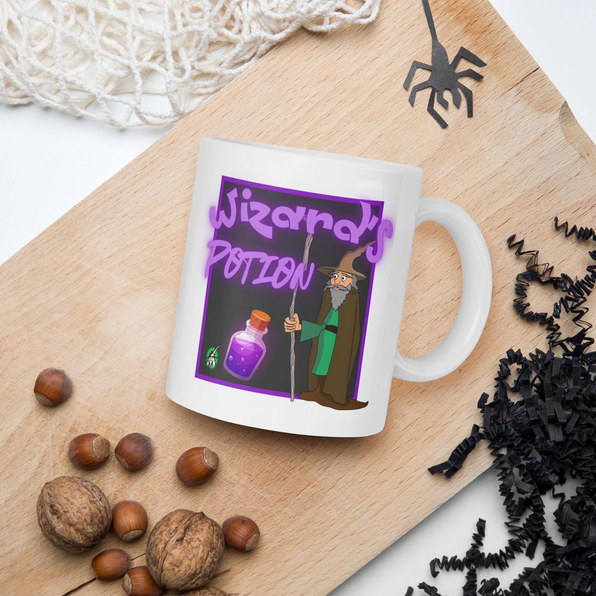White Wizard Prints mug with cartoon wizard and 'Wizard's Potion' text on a wooden board with nuts and spider decorations.