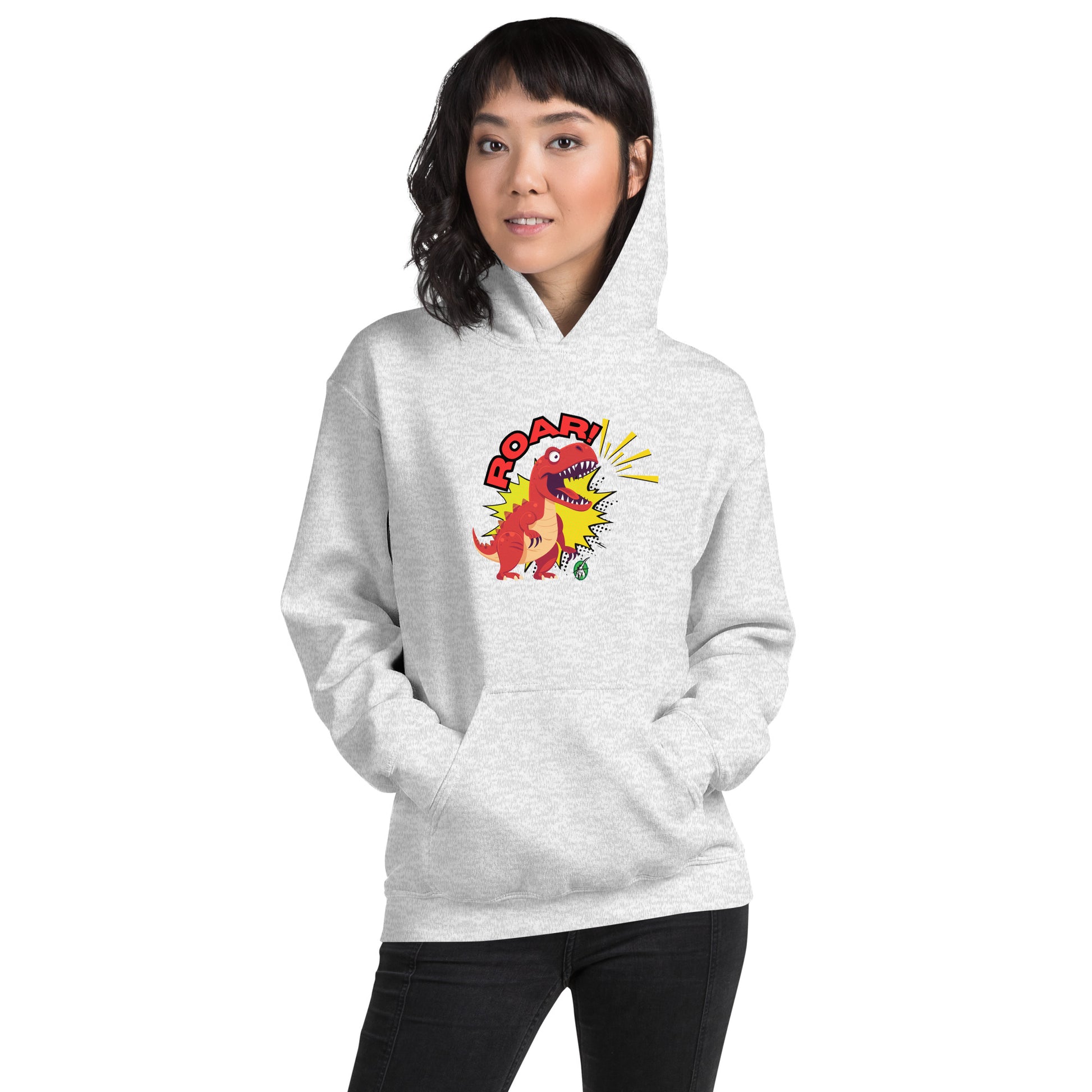 A woman standing wearing an ash hoodie with a printed graphic of a red roaring cartoon dinosaur and the word Roar! Designed by Wizard Prints