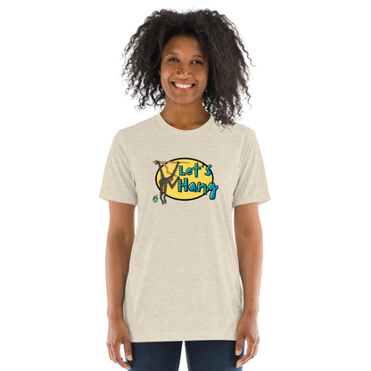 A woman standing wearing a beige tee shirt with a printed graphic of a monkey hanging on a branch with the words, Let's Hang. Designed by Wizard Prints