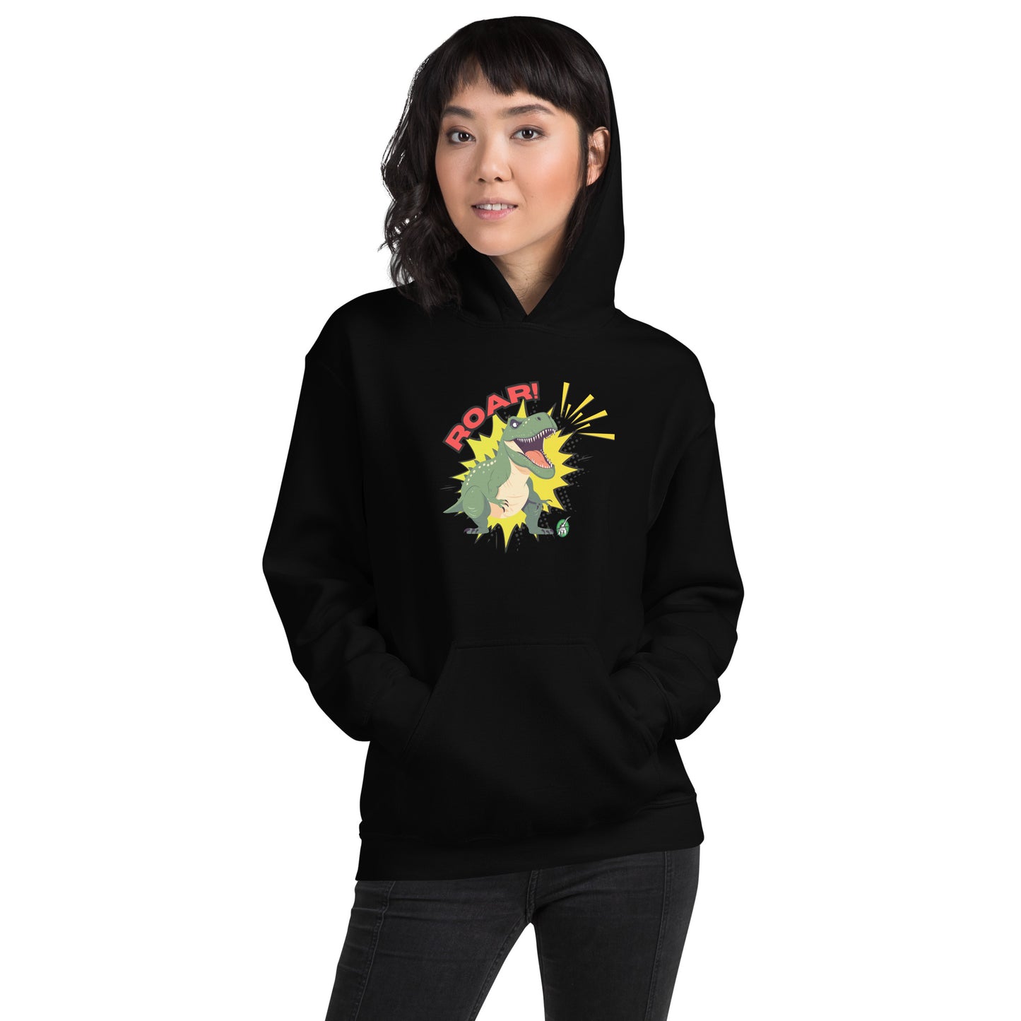 A woman standing wearing a black hoodie with a printed graphic of a green roaring cartoon dinosaur and the word Roar! Designed by Wizard Prints