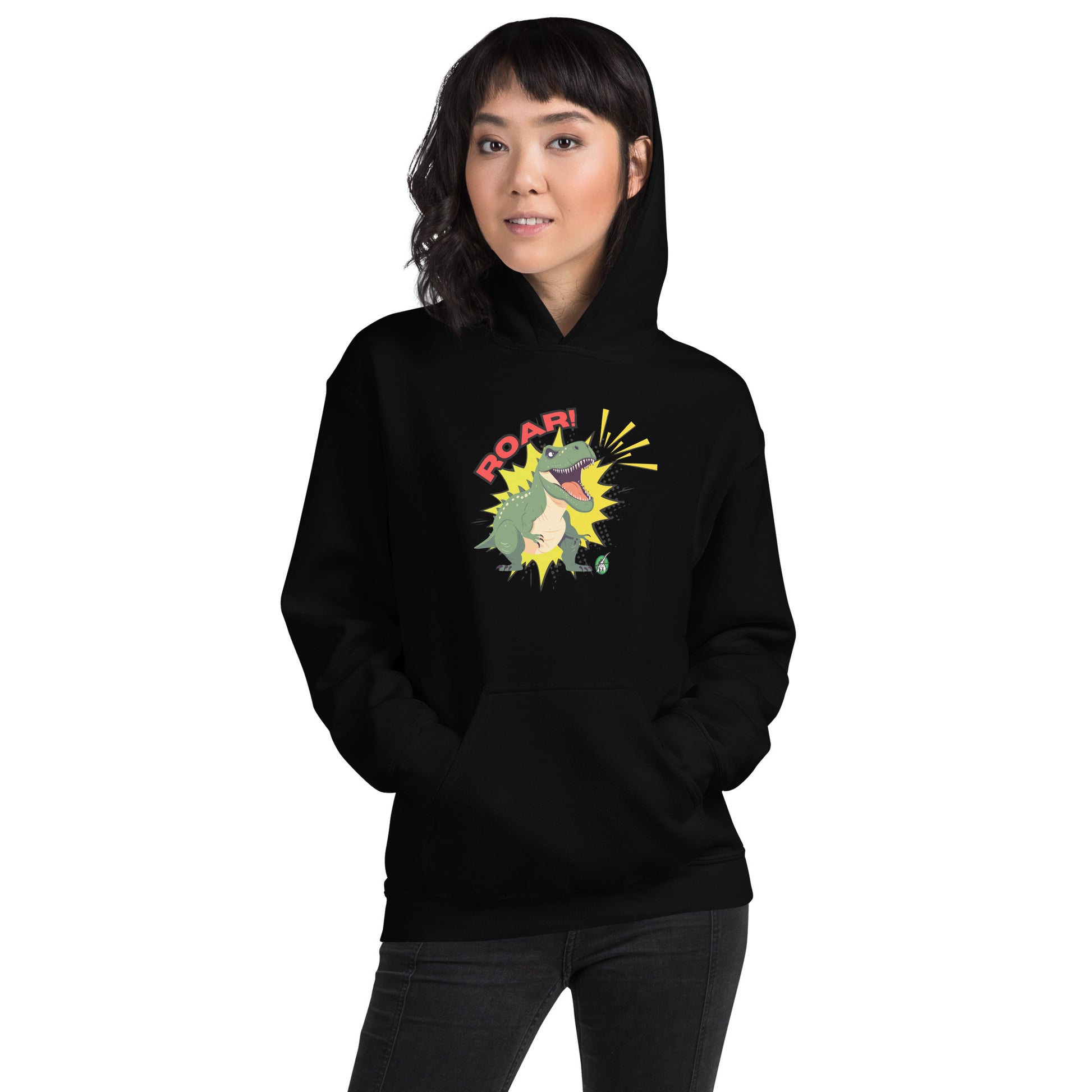 A woman standing wearing a black hoodie with a printed graphic of a green roaring cartoon dinosaur and the word Roar! Designed by Wizard Prints
