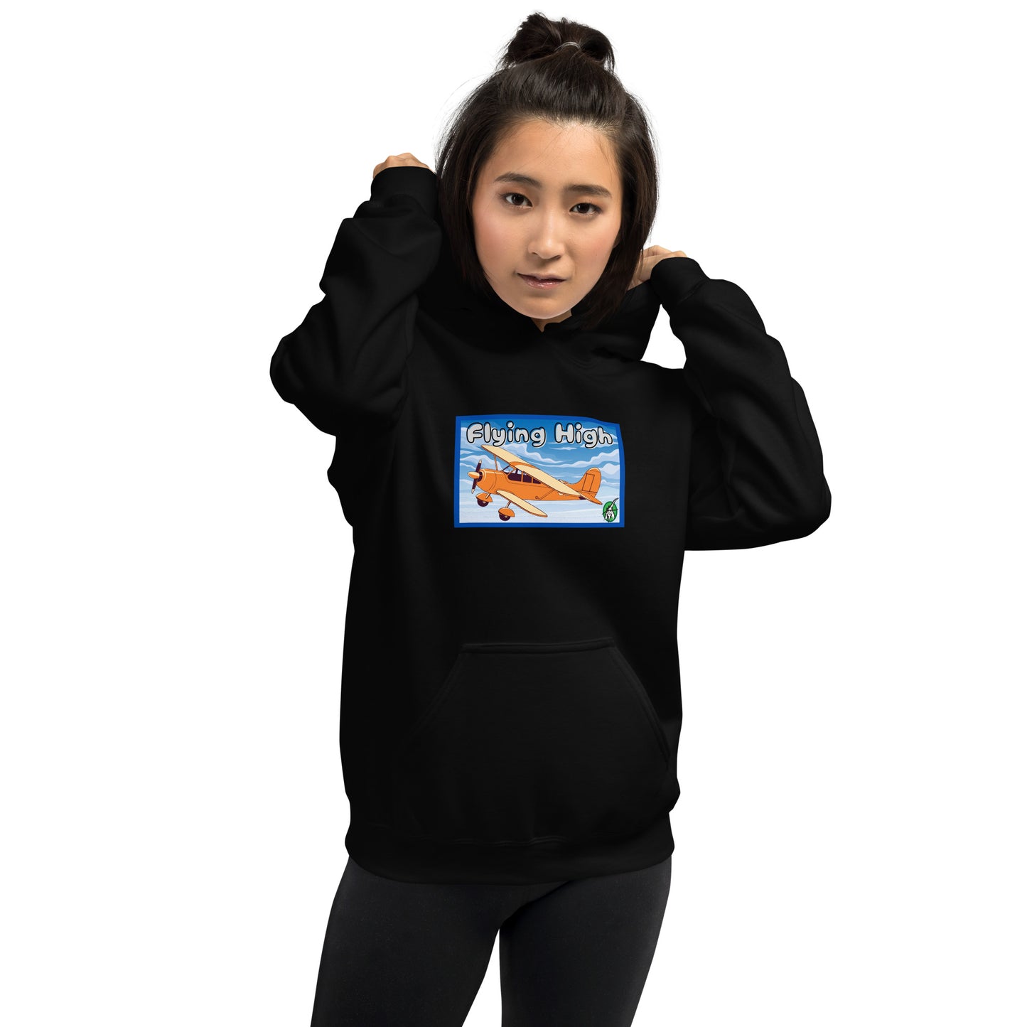 A woman standing wearing a black hoodie with the printed graphic of a vintage airplane and the words, Flying High, by Wizard Prints.