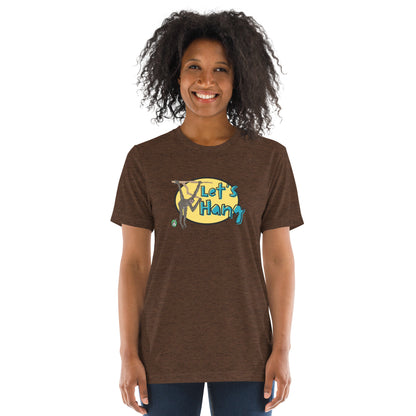 A woman standing wearing a brown tee shirt with a printed graphic of a monkey hanging on a branch with the words, Let's Hang. Designed by Wizard Prints