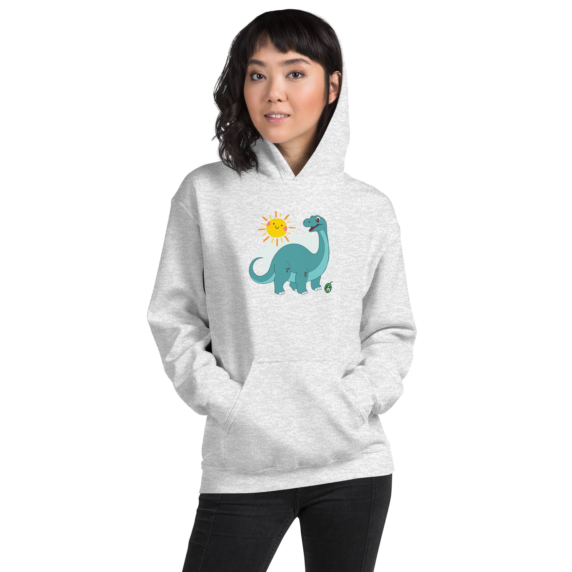 A woman standing wearing an ash hoodie with a printed graphic of a smiling cartoon dinosaur and the sun. Designed by Wizard Prints.