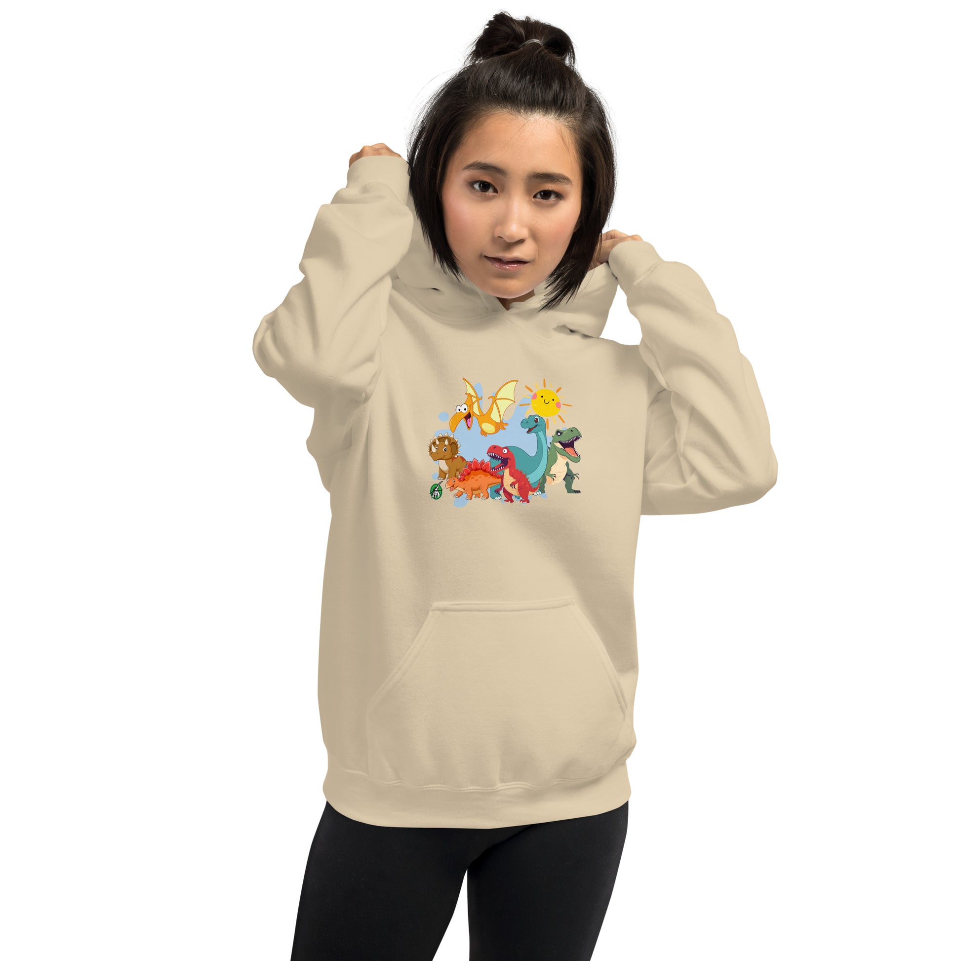 A woman standing wearing a beige hoodie with a printed graphic of different colorful dinosaur types and the sun. Designed by Wizard Prints.
