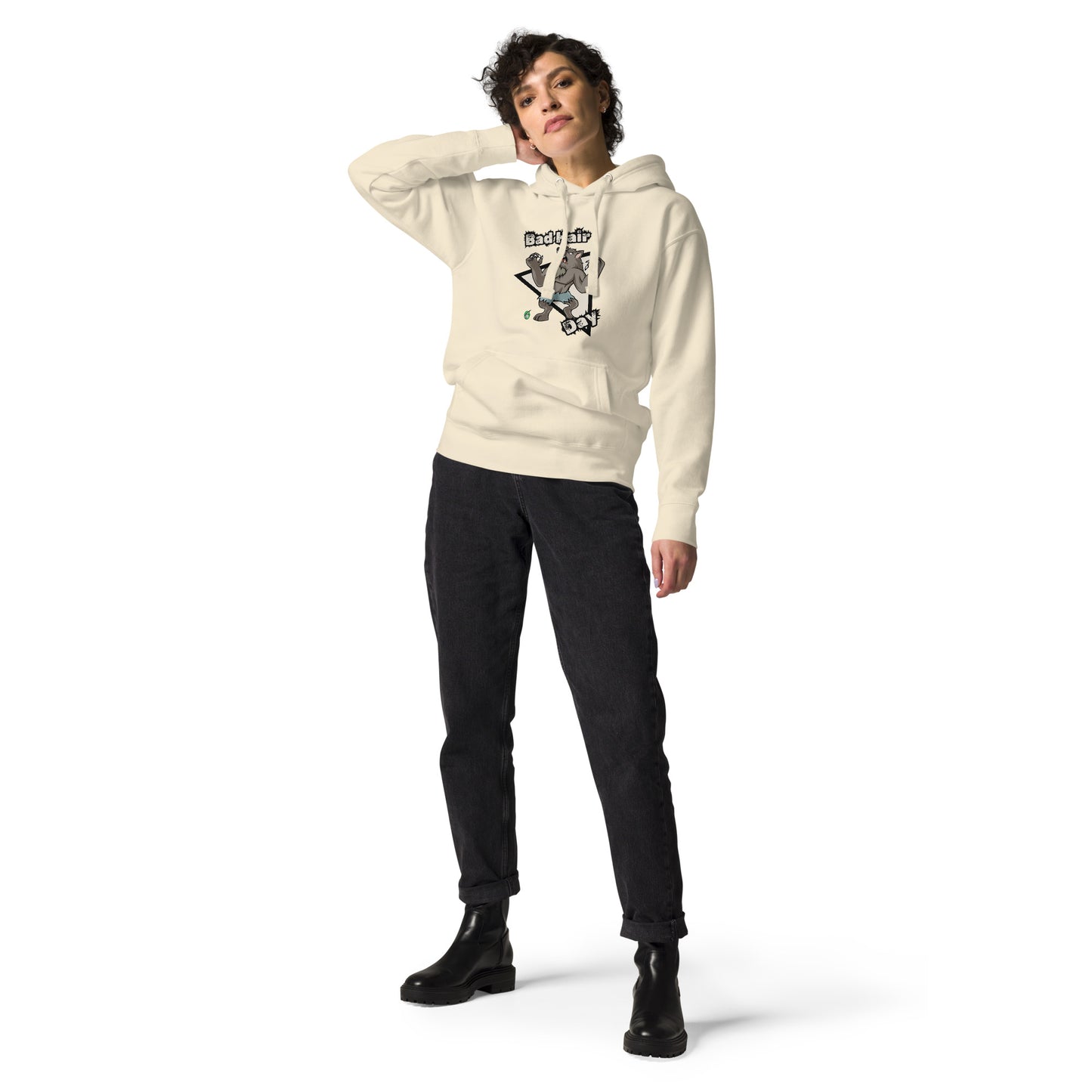 A woman standing wearing a beige hoodie with a printed graphic of a werewolf with the words, Bad Hair Day. Designed by Wizard Prints