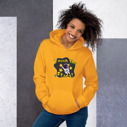 A woman standing wearing a gold hoodie with a printed graphic of a cartoon astronaut and the words, Touch the Stars. Designed by Wizard Prints.
