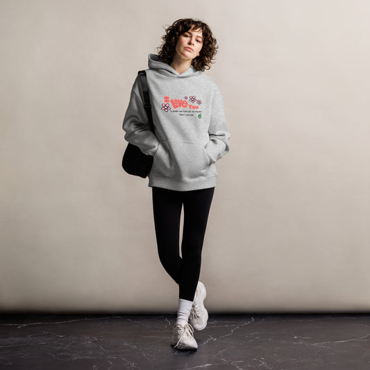 A woman standing wearing a grey hoodie by Wizard Prints featuring the bold text 'I Love You' and the plain text 'If people can hate for no reason, then I can love.'