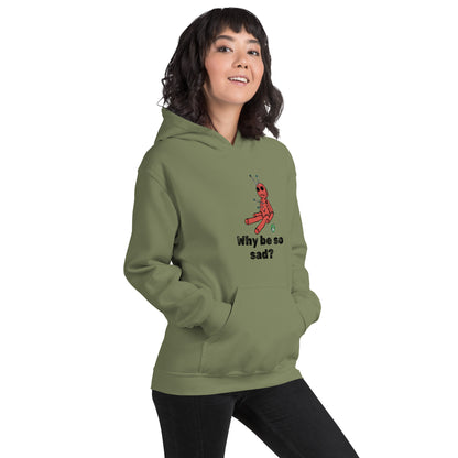 A woman standing wearing a military green hoodie with a printed graphic of a voodoo doll and the words, Why be so sad? Designed by Wizard Prints.