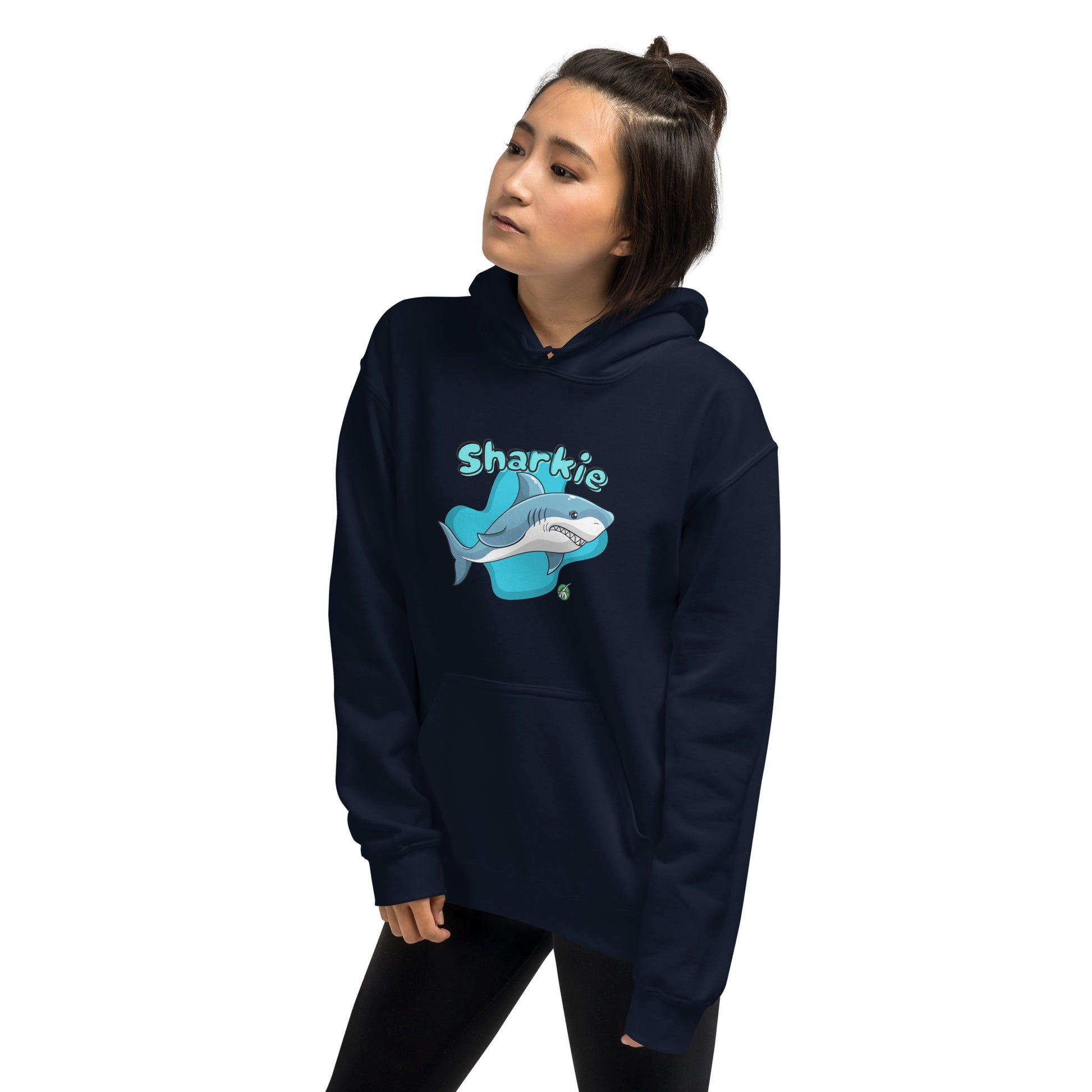 A woman standing wearing a navy blue hoodie with a printed graphic of a cartoon shark and the word, Sharkie. Designed by Wizard Prints.