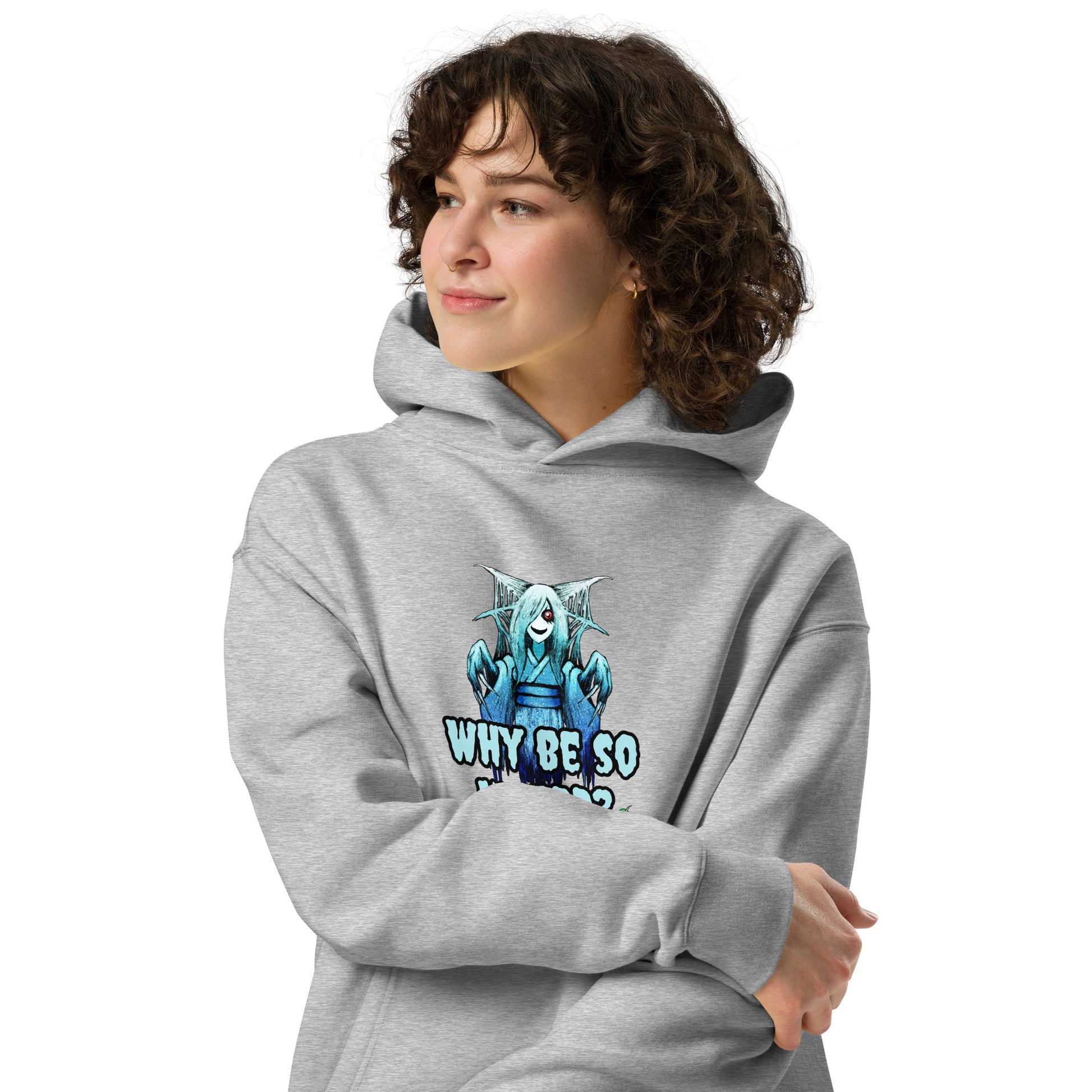 A woman standing wearing a grey hoodie by Wizard Prints featuring a printed graphic of a blue ghost girl with the words, Why Be So Weird?.