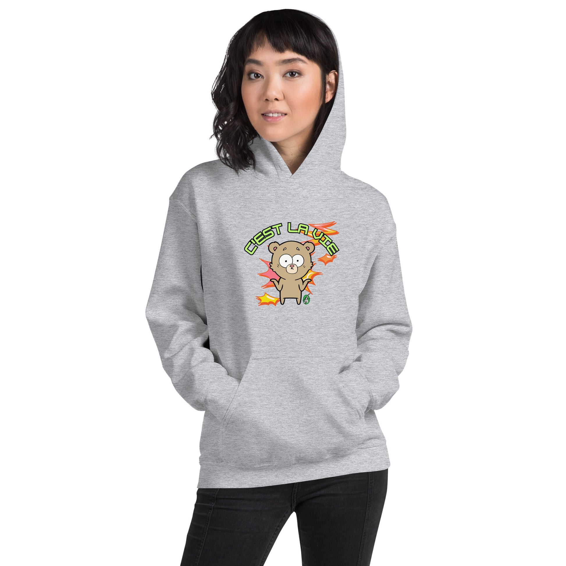 A woman standing wearing a grey hoodie by Wizard Prints featuring a printed graphic of a shrugging cartoon bear and the words, C'est La Vie.