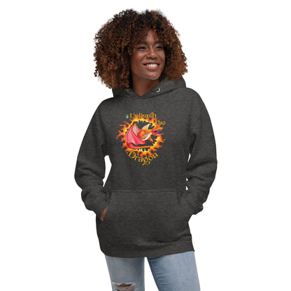 A woman standing wearing a dark grey hoodie with a printed graphic of a fire-breathing dragon with the words, 'Unleash the Dragon'. Designed by Wizard Prints.