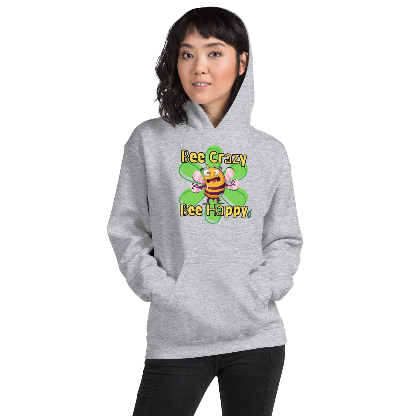 A woman standing wearing a light grey hoodie with a printed graphic of a bee with the words, 'Bee Crazy Bee Happy'. Designed by Wizard Prints.