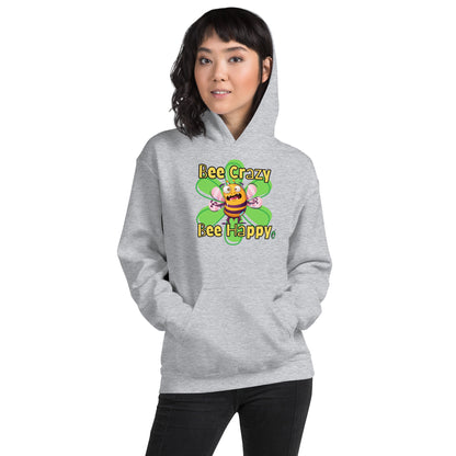 A woman standing wearing a light grey hoodie with a printed graphic of a bee with the words, 'Bee Crazy Bee Happy'. Designed by Wizard Prints.
