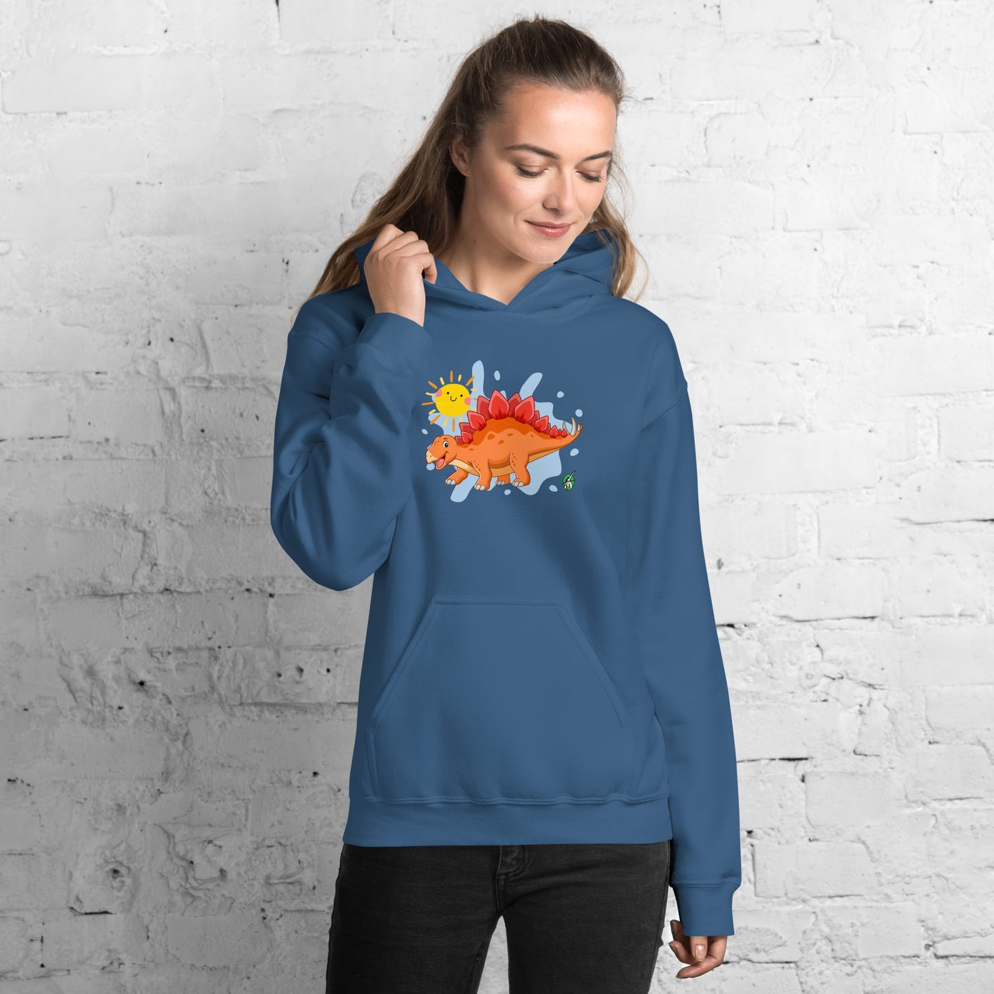 A woman standing wearing an indigo hoodie with the printed graphic of an orange cartoon dinosaur and the sun, by Wizard Prints.