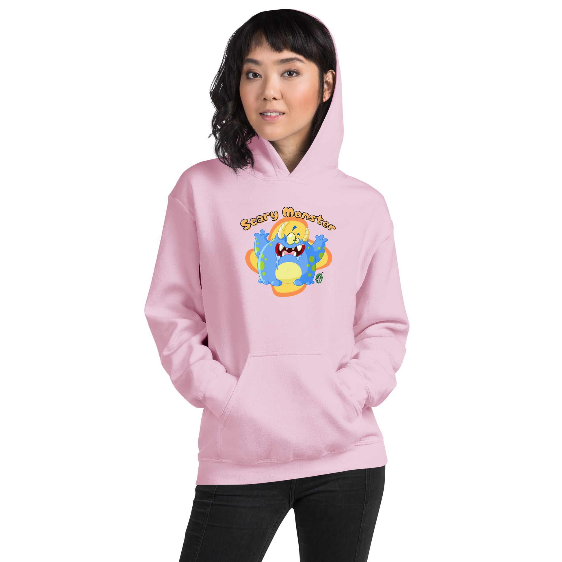 A woman standing wearing a light pink hoodie with a printed graphic of a cartoon monster and the words, Scary Monster. Designed by Wizard Prints.