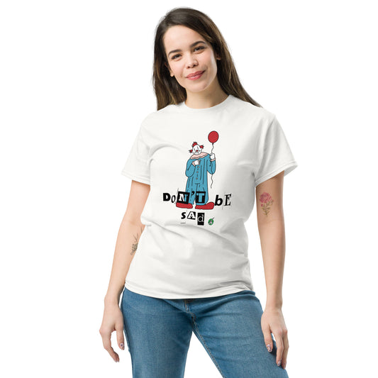 A woman standing and wearing a white t-shirt with a printed graphic of a clown holding a balloon with the words, "Don't be sad". Designed by Wizard Prints