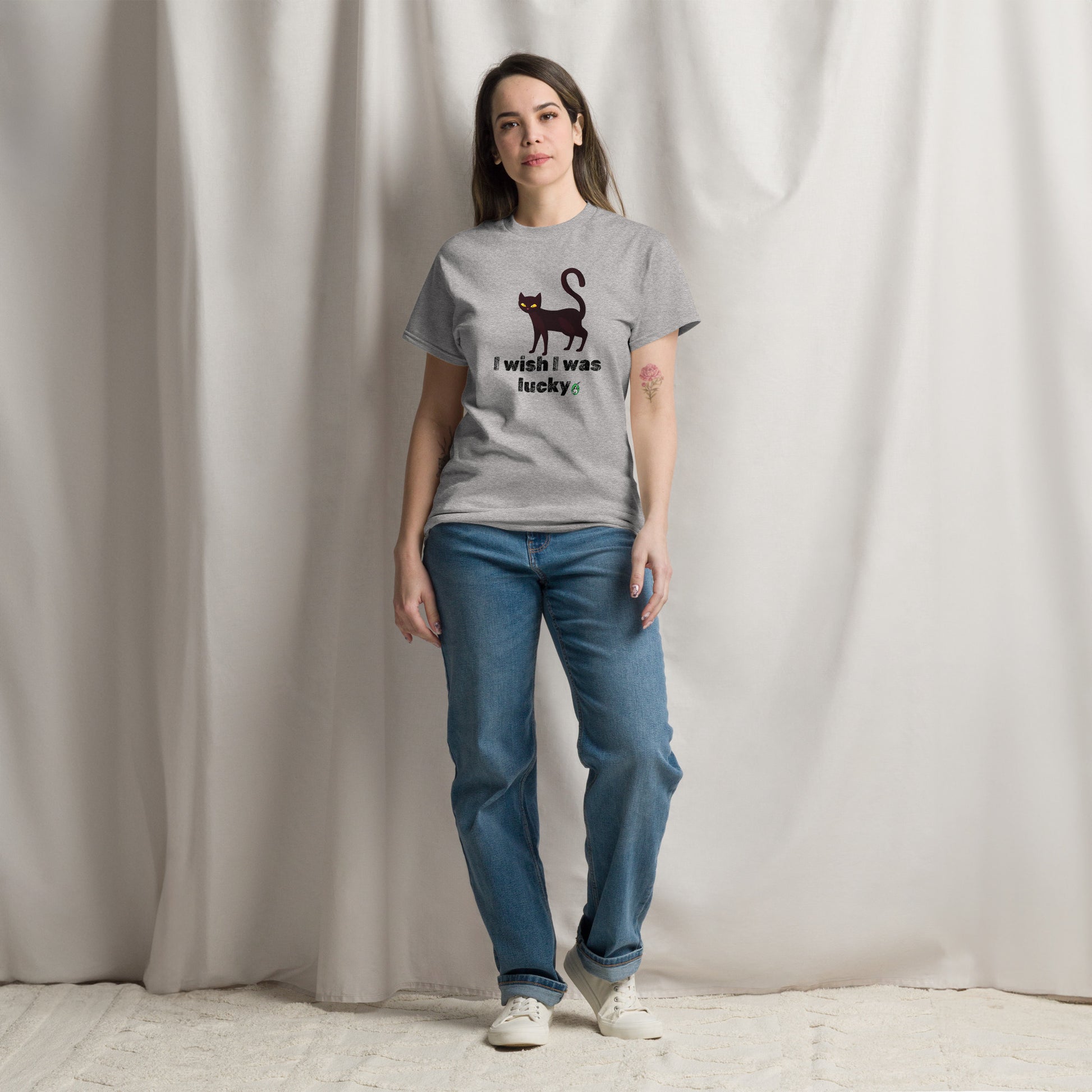 A woman standing wearing a grey t-shirt with a printed graphic of a cat with the words, 'I Wish I Was Lucky'. Designed by Wizard Prints.