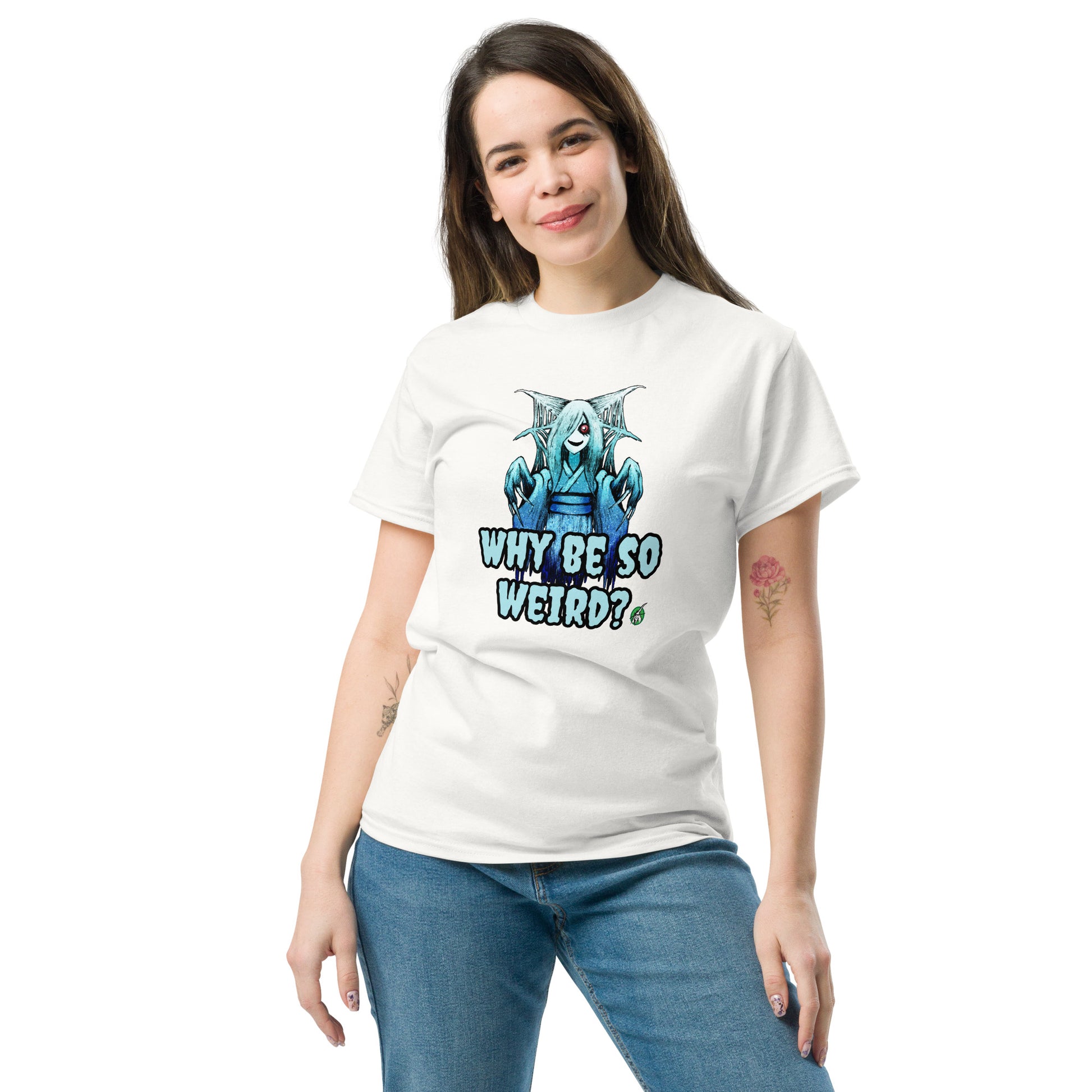 A woman standing and wearing a white t-shirt with a printed graphic of a blue ghost girl with the words, 'Why Be So Weird?'. Designed by Wizard Prints.